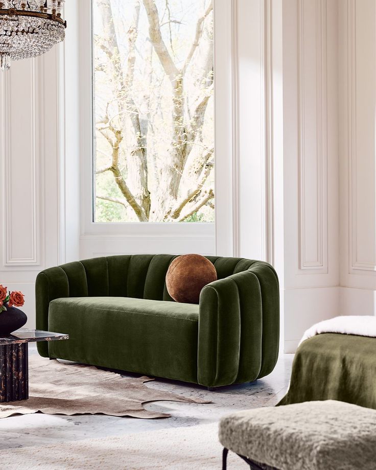 a living room with green velvet furniture and a chandelier