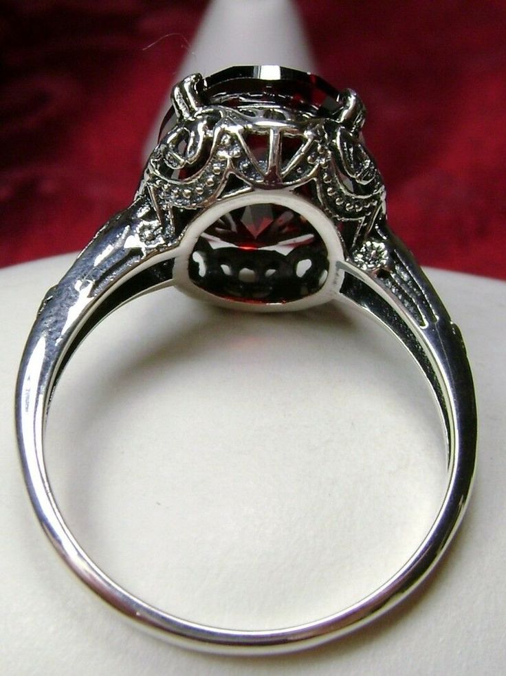 6ct. Natural or Red Garnet Cubic Zirconia (CZ) Solid Sterling Silver RingEdward Design#D70 This filigree ring is an Edwardian antique reproduction in sterling silver, set with a choice of a Natural or a Red Garnet CZ gemstone solitaire. This full cut oval gem is 14mm x 10mm. This ring sits 7mm off the finger. The inside of the band is marked 925 for solid sterling silver. Notice the beautiful floral leaf design of the silver filigree setting and the etched band. This ring is part of our Edward s Silver Garnet Ruby Ring With Center Stone, Classic Silver Filigree Ring Collectible, Antique Silver Diamond Ring Collectible, Classic Ruby Ring With Round Stone For Formal Occasions, Classic Garnet Round Stone Jewelry, Vintage Garnet Ruby Ring With Intricate Design, Silver-colored Ruby Diamond Ring In Round Cut, Formal Silver Ruby Ring With Cubic Zirconia, Vintage Round Diamond Ring With Accent Stones