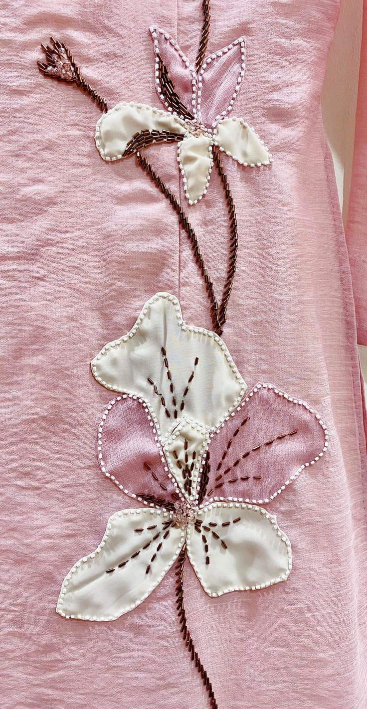 an embroidered pink dress with white flowers on it