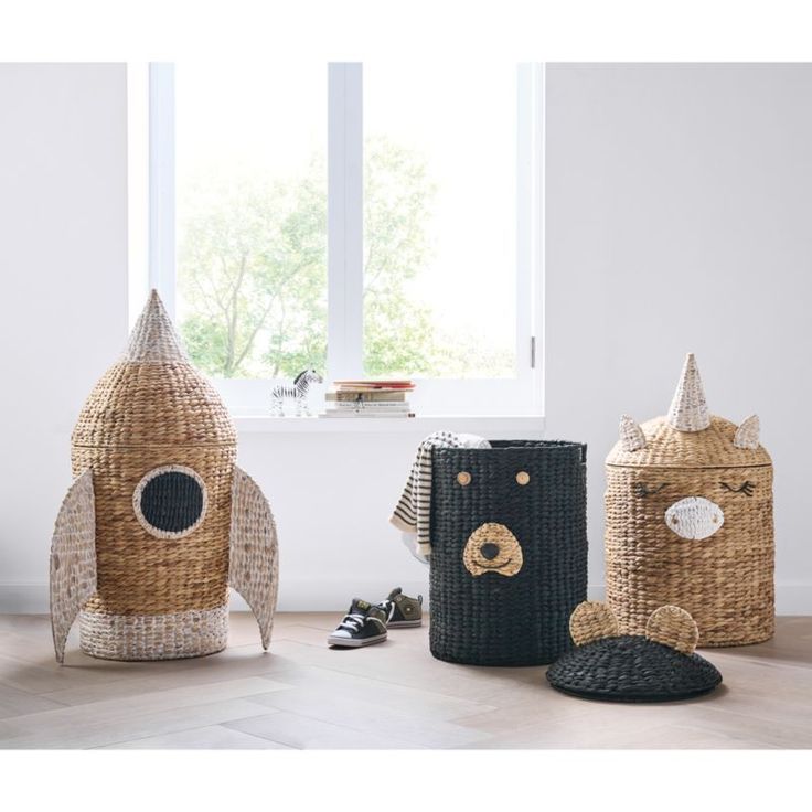 three woven objects are sitting on the floor in front of a window, one is shaped like a rocket ship