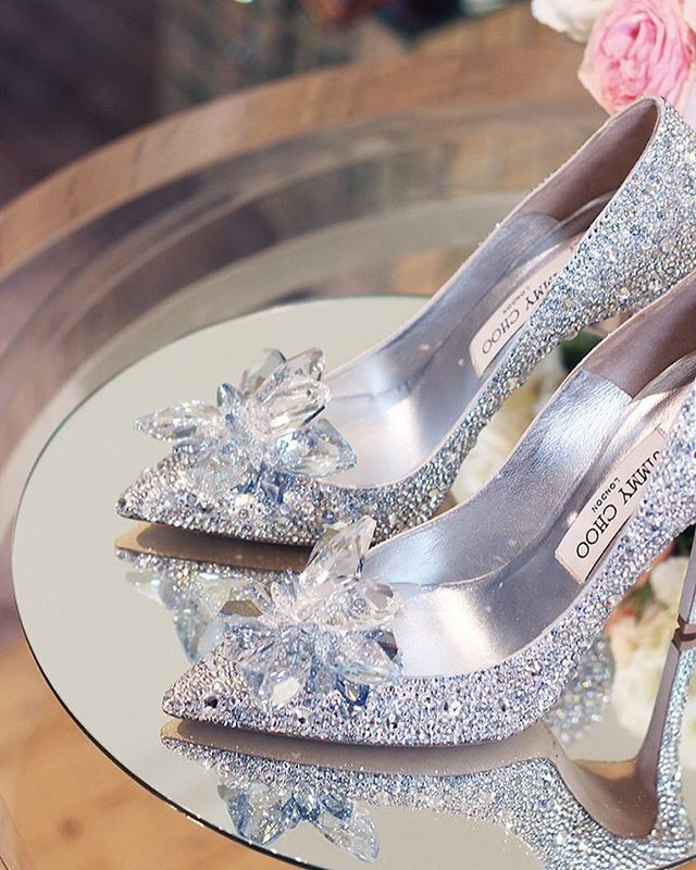 two pairs of high heeled shoes with bows on them, one is silver and the other is white