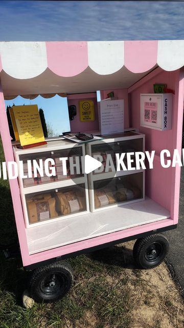 a pink and white food cart sitting on top of a grass covered field