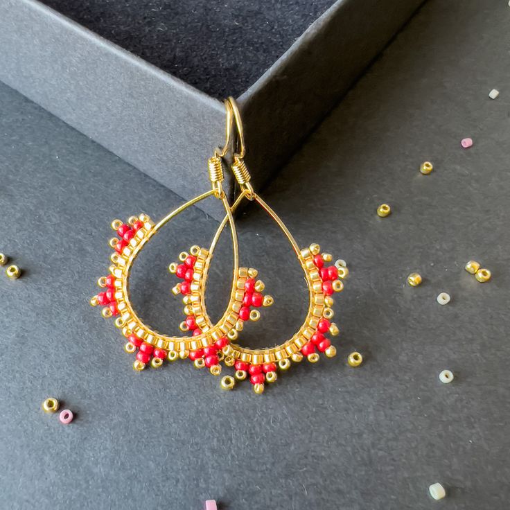 Ear wire 14mm , Teardrop charm 17mm Color: Miyuki Delica Bead galvanized bright gold with ruby , galvanized gold toho seed bead. These earrings epitomize craftsmanship, utilizing top-tier branded beads such as Miyuki Delica beads and TOHO seed beads. Meticulously handcrafted with a robust beading thread, these earrings guarantee enduring shape retention and bead stability, even with continuous wear. A diverse spectrum of color combinations is available to cater to individual preferences, while all metallic components are expertly fashioned from high-quality brass. Hypoallergenic earring hooks prioritize wearer comfort and safety. Each design in the shop reflects a profound commitment to artistry, characterized by painstaking attention to detail.  Importantly, please consider potential slig Gold Round Beads Earrings For Gift, Minimalist Dangle Earrings With Tiny Beads, Dainty Handmade Small Hoop Earrings, Yellow Gold Round Bead Earrings As Gift, Yellow Gold Earrings With Round Beads As Gift, Dainty Gold Beaded Earrings, Handmade Minimalist Beaded Dangle Earrings, Small Hoop Wire Wrapped Beaded Earrings As Gift, Handmade Gold Hoop Earrings For Festive Occasions