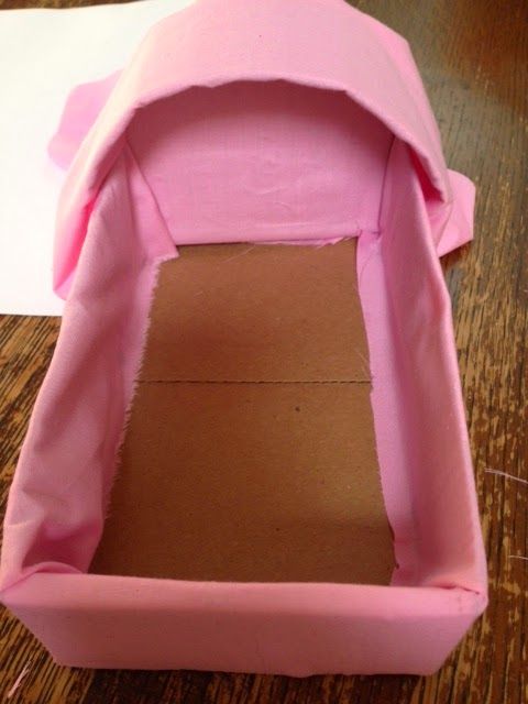 the inside of a pink paper mache box on top of a wooden table next to a piece of cardboard