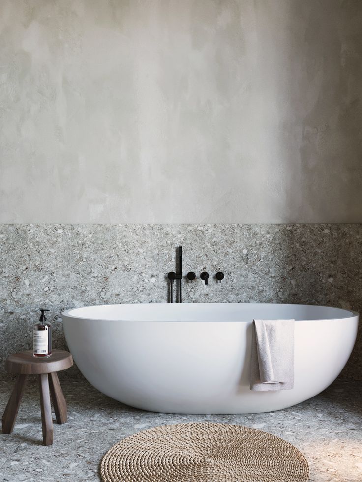 a white bath tub sitting on top of a bathroom floor next to a wooden stool