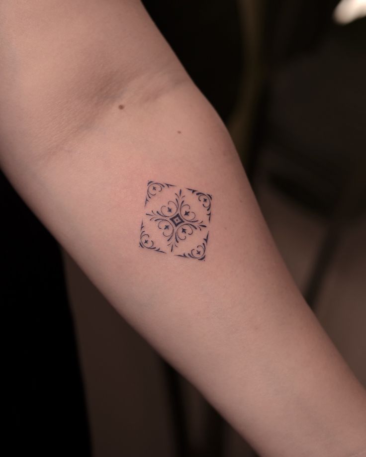 a small tattoo on the arm of a woman's left arm, with an ornamental design