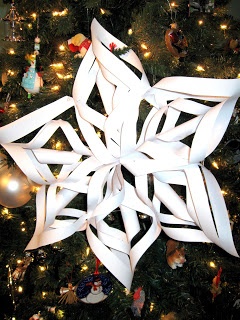 a paper snowflake is hanging from a christmas tree