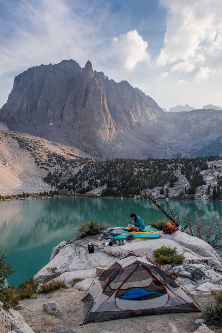 a man sitting on top of a rock next to a lake