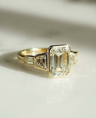 an emerald and diamond ring sitting on top of a table