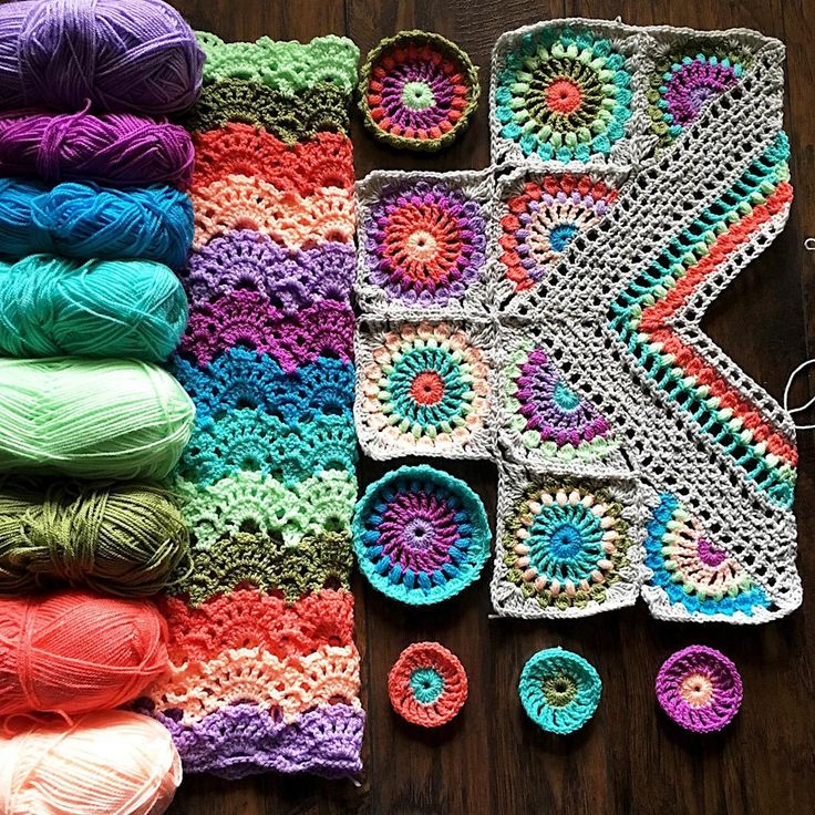 crocheted granny afghans and balls of yarn are arranged on a wooden surface