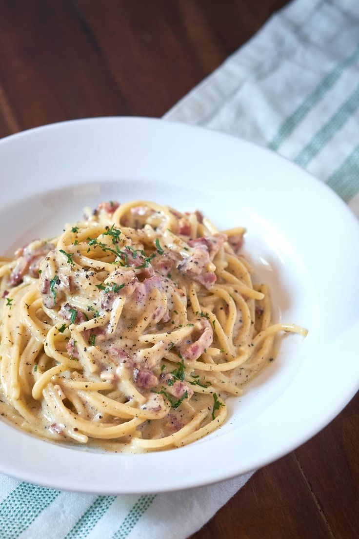 a white bowl filled with pasta and sauce on top of a blue and white towel