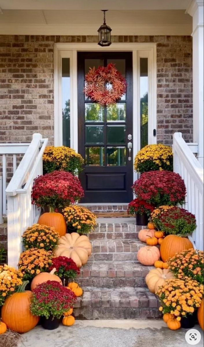 front porch decorated for fall with pumpkins and flowers