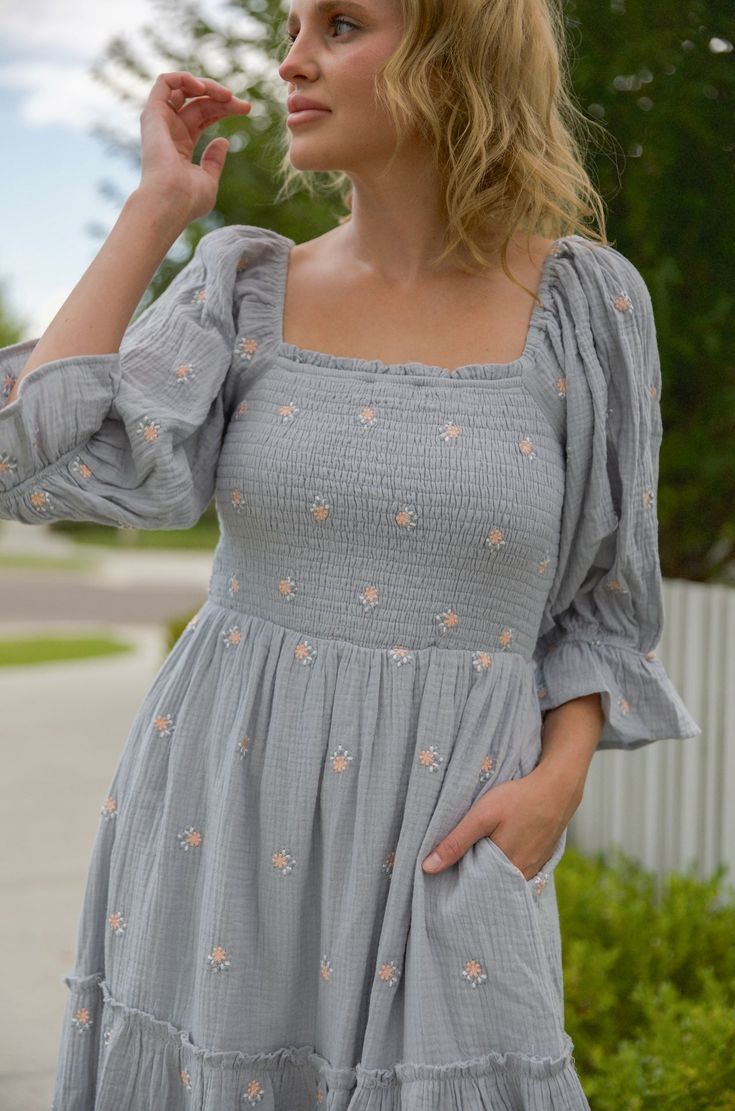 This stunning puff sleeve midi dress features a smocked bodice, embroidered flowers, tiered skirt and pockets for an ultra-feminine look. The puff sleeve midi dress is perfect for any special occasion. This dress pairs comfort and style for a standout look that will earn you compliments. steel blue embroidered florals smocked top square neckline lined pockets midi maxi length true to size Self: 100% cotton / Lining: 100% polyester hand wash cold model is wearing a small. Height is 5'5" Spring Smock Dress With Square Neck, Spring Dress With Smocked Cuffs And Square Neck, Square Neck Dresses With Smocked Cuffs For Day Out, Spring Smocked Dress With Square Neck And Smocked Cuffs, Modest Smocked Dress With Puff Sleeves, Midi Dress With Smocked Cuffs For Garden Party, Summer Dress With Balloon Sleeves And Smocked Cuffs, Feminine Spring Midi Dress With Smocked Cuffs, Feminine Midi Smocked Dress With Smocked Cuffs