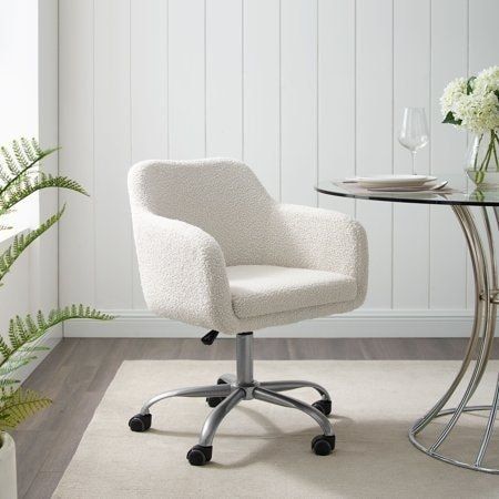 a white chair sitting in front of a glass table with flowers on top of it