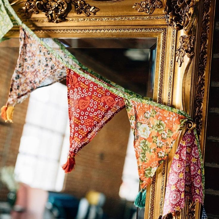 an ornate gold framed mirror with colorful cloths hanging from it