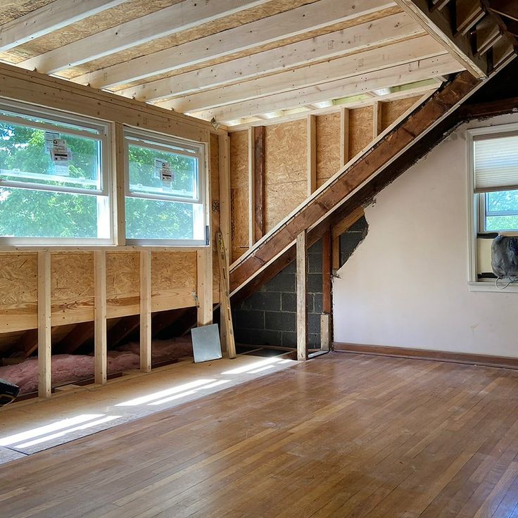 an unfinished room with wood flooring and windows