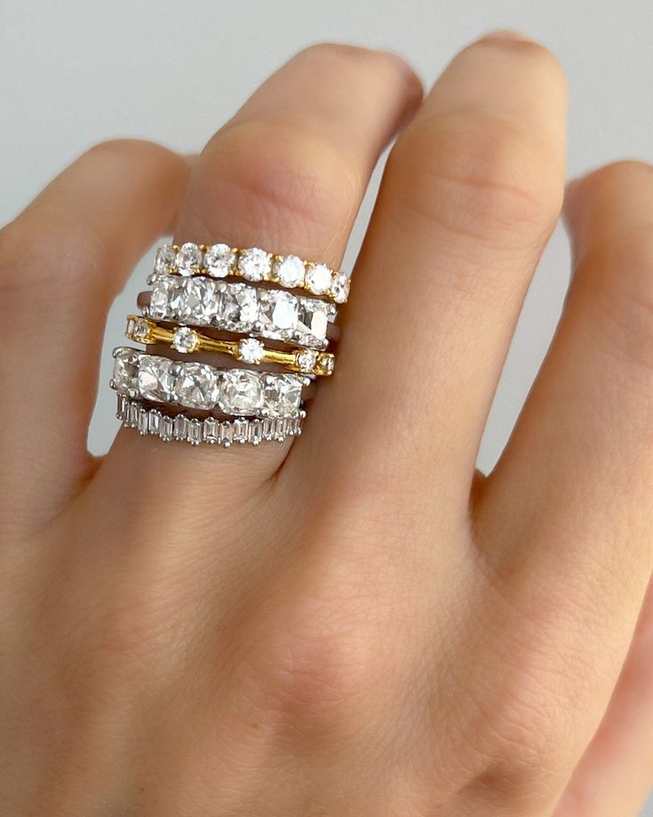 a woman's hand with three different rings on her fingers, one in gold and the other in silver