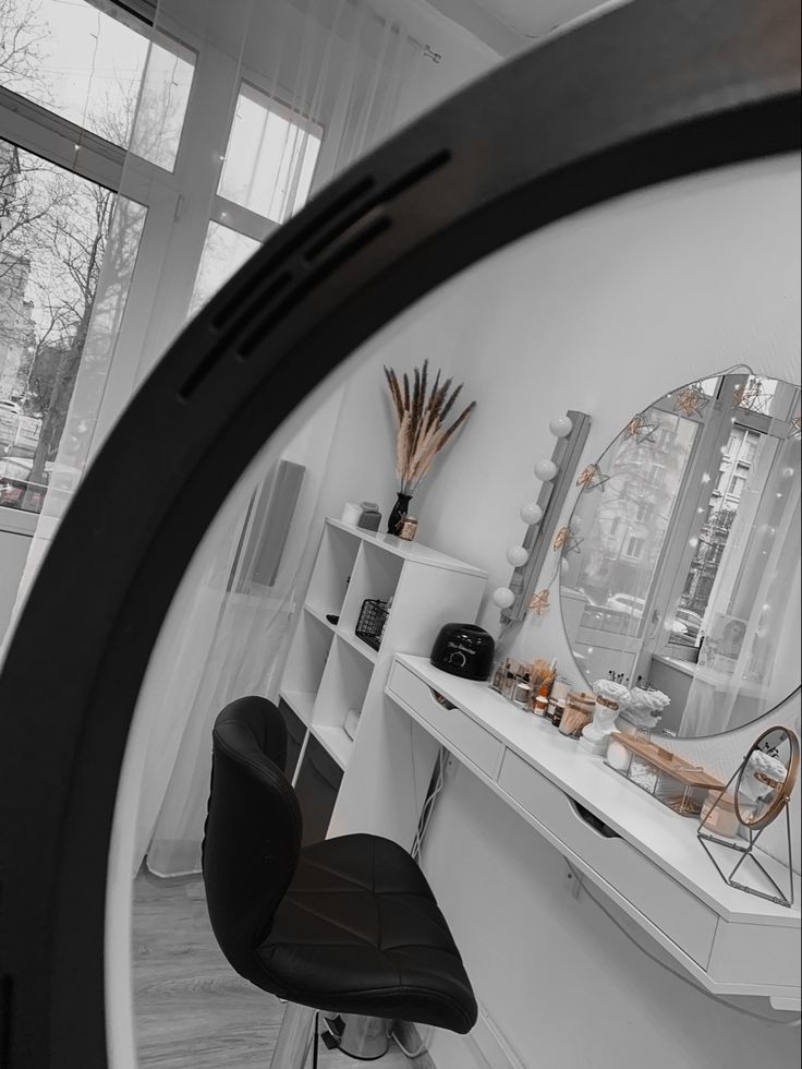 a mirror reflecting a room with a desk, chair and shelves on the wall next to it