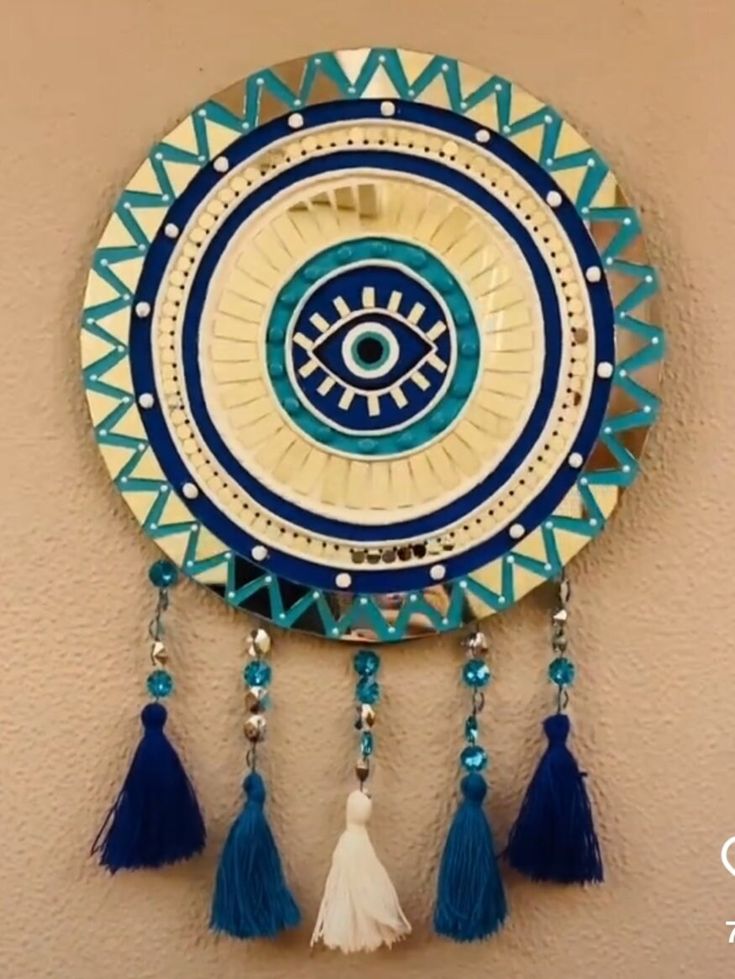 a blue and white clock with tassels hanging from it's side on a wall