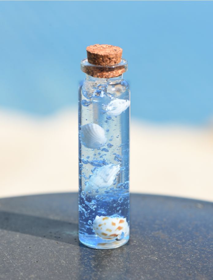 a bottle filled with water and shells on top of a table