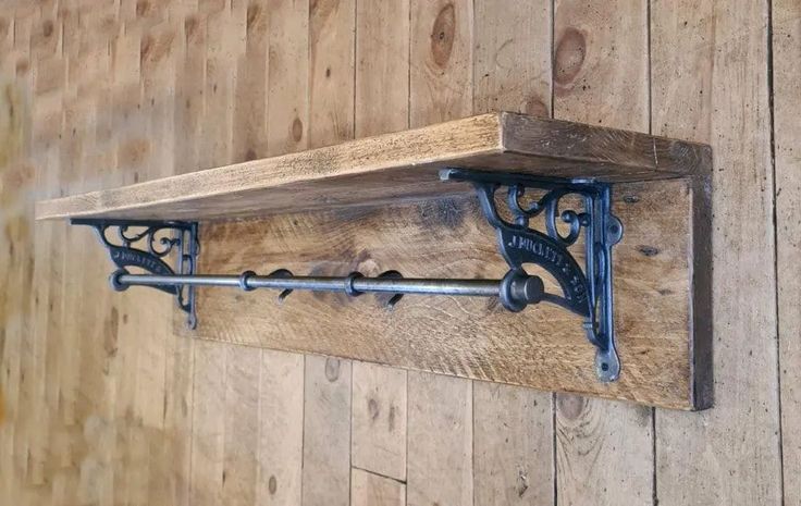 a wooden shelf with two metal brackets on the top and an iron pipe in the middle