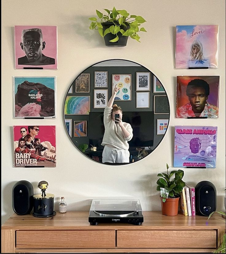 a woman taking a selfie in front of a mirror with pictures on the wall