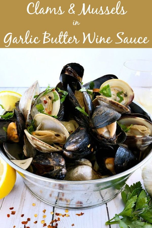 clams and mussels in garlic butter wine sauce on a white wooden table