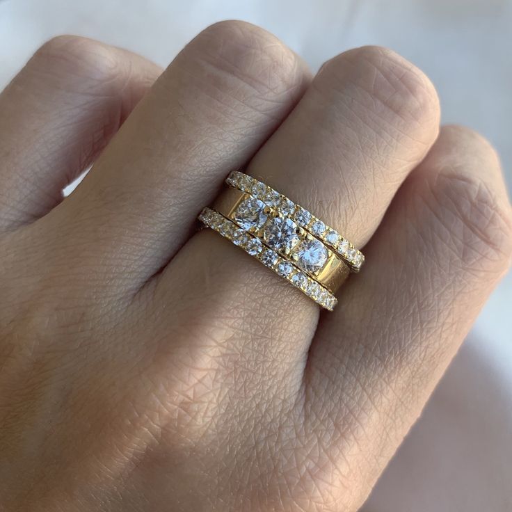 a woman's hand with a diamond ring on top of her finger and an engagement band in the middle