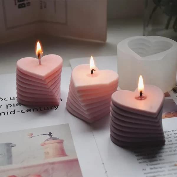 three heart shaped candles sitting on top of a table next to a magazine and some flowers