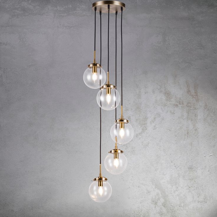 a chandelier with five glass globes hanging from it's brass finish