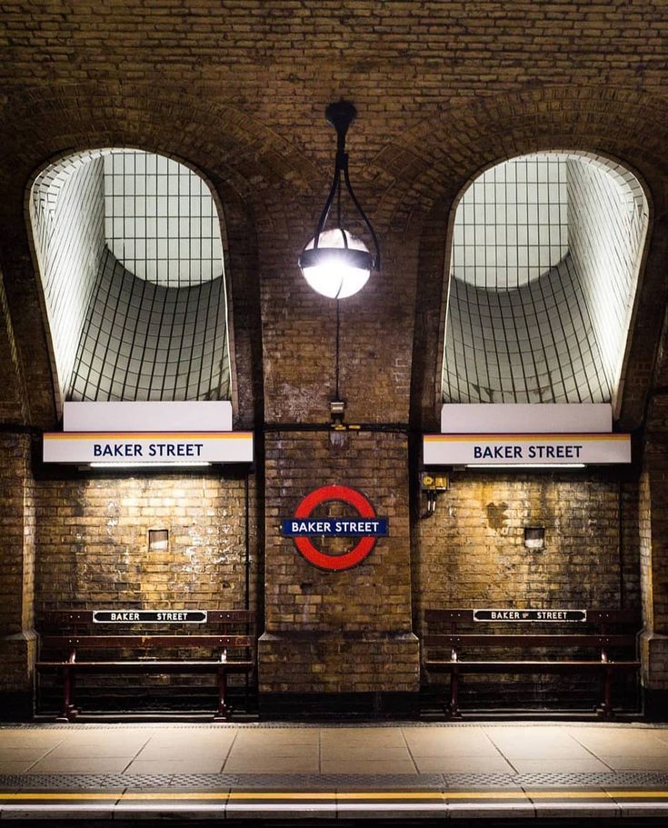 an empty train station with two benches and a light hanging from the ceiling above it