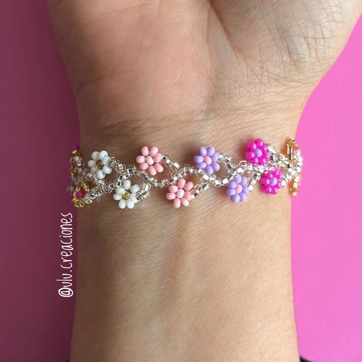 a woman's hand holding a bracelet with flowers on it