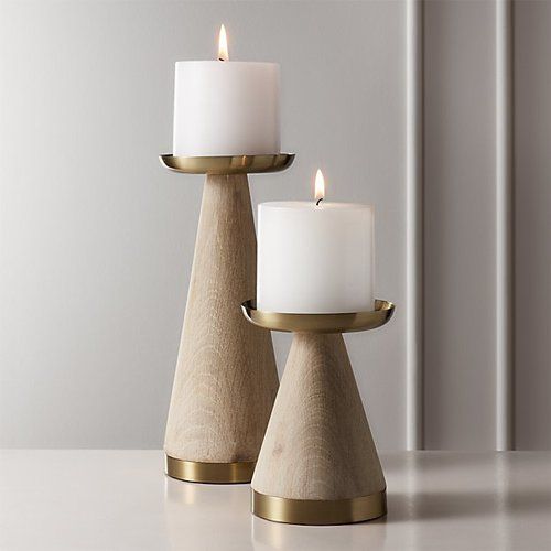 two candles sitting on top of each other in front of a wall with white walls