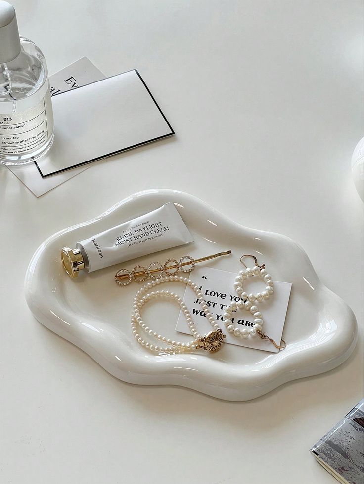 a white tray topped with lots of jewelry next to a bottle of water and a pair of earrings