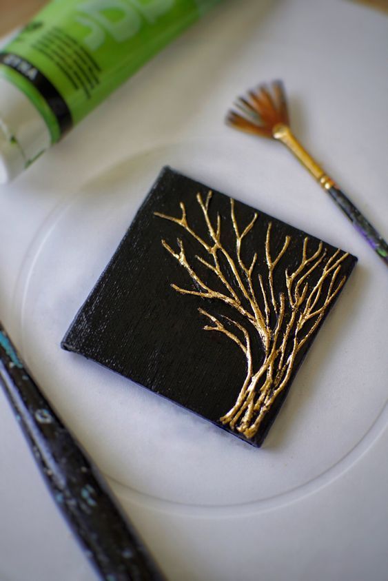 a white plate topped with a black and gold napkin next to paintbrushes on top of a table