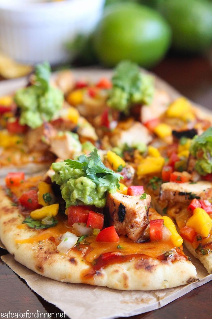 a pizza with chicken, avocado and salsa on it sitting on a table