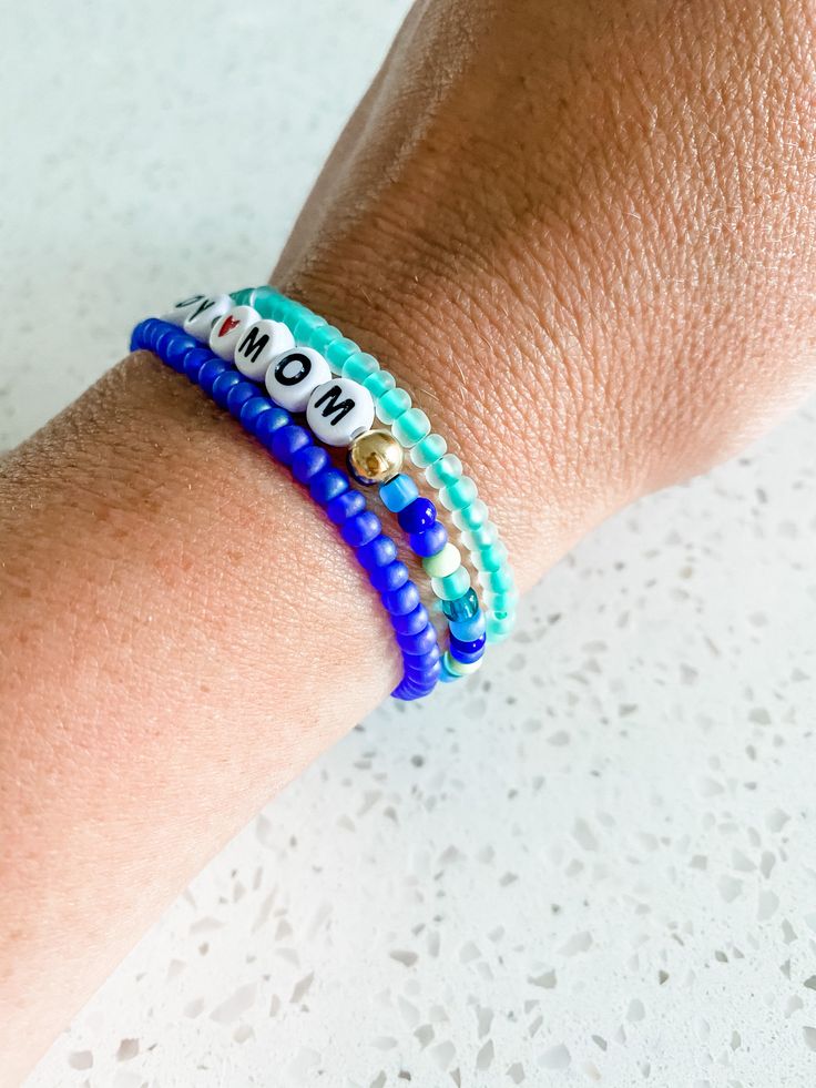 "BOY MOM BRACELET -This is for one BOY MOM bracelet. -This bracelet is an assortment of blue and green colors shown in the pictures with gold beads beside the words and a heart as the space in between. -This bracelet is a stretchy material and is easy to get on and off. -This bracelet comes in small adult, medium adult or large adult sizes. The medium adult size is 7\" and is an average sized wrist. If you would like to measure your wrist size exactly, we can make it to your size! Just add how m Personalized Blue Friendship Bracelets, Blue Stackable Stretch Bracelet For Everyday, Everyday Stackable Blue Bracelets, Blue Friendship Bracelets For Mother's Day Gift, Blue Stackable Beaded Bracelets As Gift, Adjustable Blue Stackable Stretch Bracelet, Blue Adjustable Stackable Stretch Bracelet, Adjustable Blue Name Bracelet With Colorful Beads, Personalized Blue Bracelets For Everyday Wear