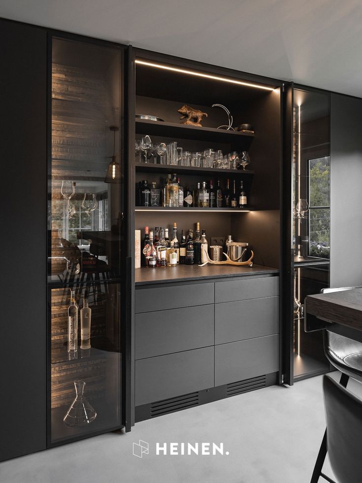 an open cabinet in the middle of a dining room with black chairs and glassware