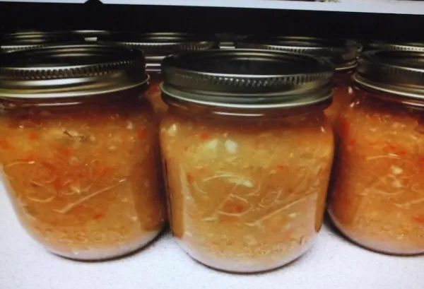 four jars filled with food sitting on top of a counter next to a stovetop