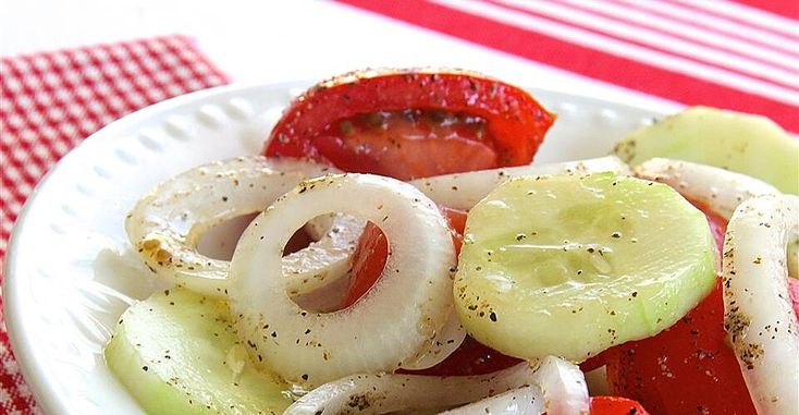 a white plate topped with sliced vegetables on top of a red and white checkered table cloth