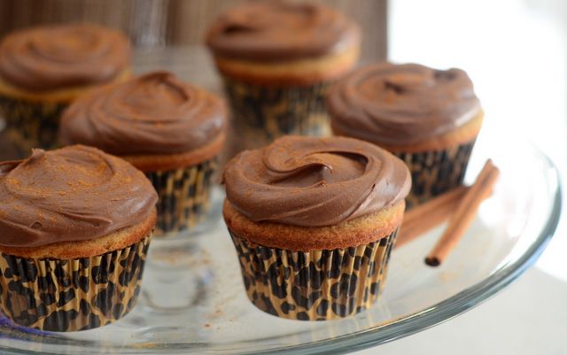 cupcakes with chocolate frosting and cinnamon sticks on a glass platter, ready to be eaten