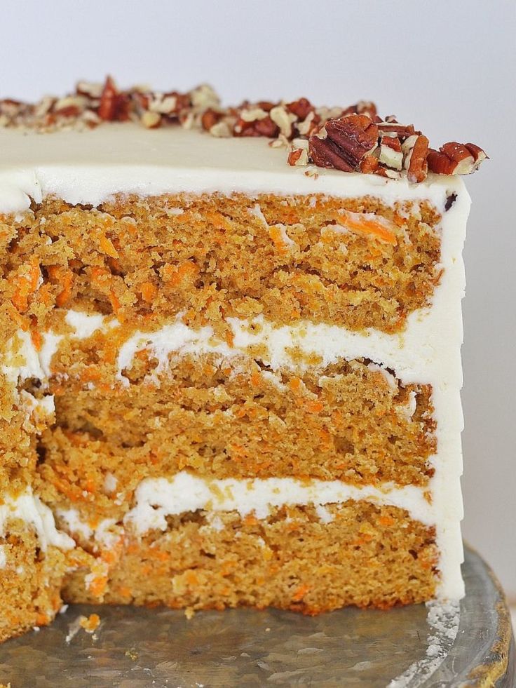 a carrot cake with white frosting and nuts on top