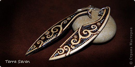 two silver and gold earrings sitting on top of a stone covered ground with brown background