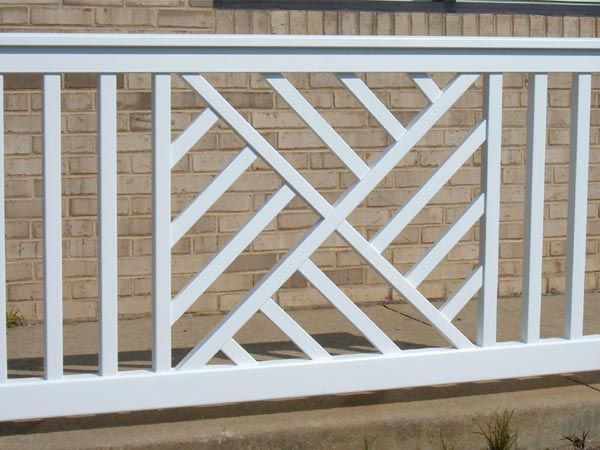 a white fence is in front of a brick wall