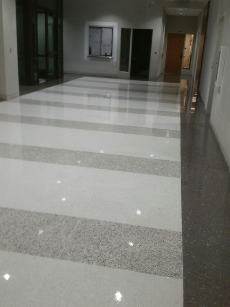 an empty hallway with white and grey striped flooring on both sides, leading to two elevators