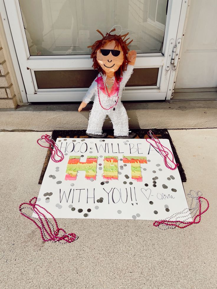 a stuffed animal sitting on the ground in front of a sign that says happy birthday with you