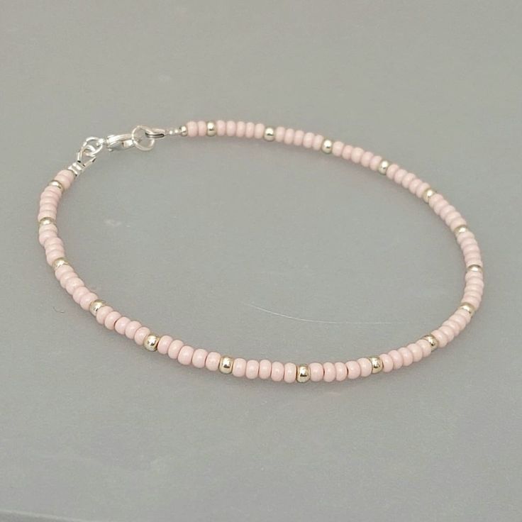 "This baby pink seed bead anklet has been lovingly made using glass 3mm opaque pink Preciosa seed beads.  Highlighted with 3mm Miyuki seed beads in a choice of silver or gold. Threaded on strong stainless steel 7 strand Tiger Tail wire and finished with silver/gold plated wire guardians and a lobster clasp, making it easy to put on & take off. With an optional 2\" Silver/gold plated extender chain so you can wear the anklet to sit where you feel most comfortable. I make these in various sizes in Pink Beaded Anklet, Cute Seed Bead Bracelets, Easy Beaded Bracelets, Pink Seed Bead Bracelet, Seed Bead Anklet, Anklets Diy, Small Bead Bracelet, Pink Beaded Bracelets, White Beads Bracelet