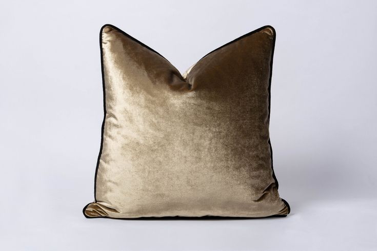 a gold velvet pillow with black piping on the front and back, against a white background