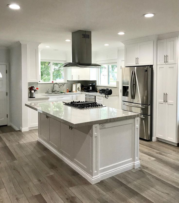 a large kitchen with an island in the middle and stainless steel appliances on both sides