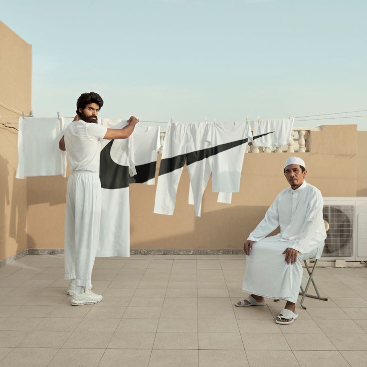 two men standing on a roof with clothes hanging out to dry in the air,